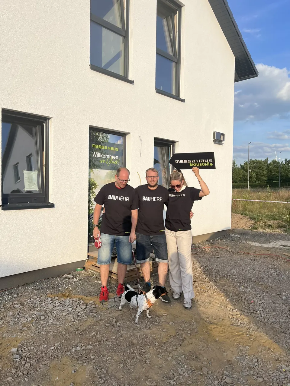Baufamilie in Bauherr-Shirts mit Hund vor ihrem massa haus in Schwerte