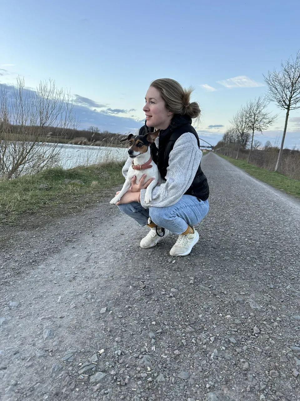 Marlen Weber hockt mit ihrem Hund auf einem Feldweg im Abendlicht